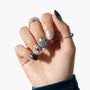 Hand with metallic blue and silver press-on nails featuring star and abstract designs