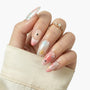 Hand with long press-on nails featuring pastel star designs and pearl accents