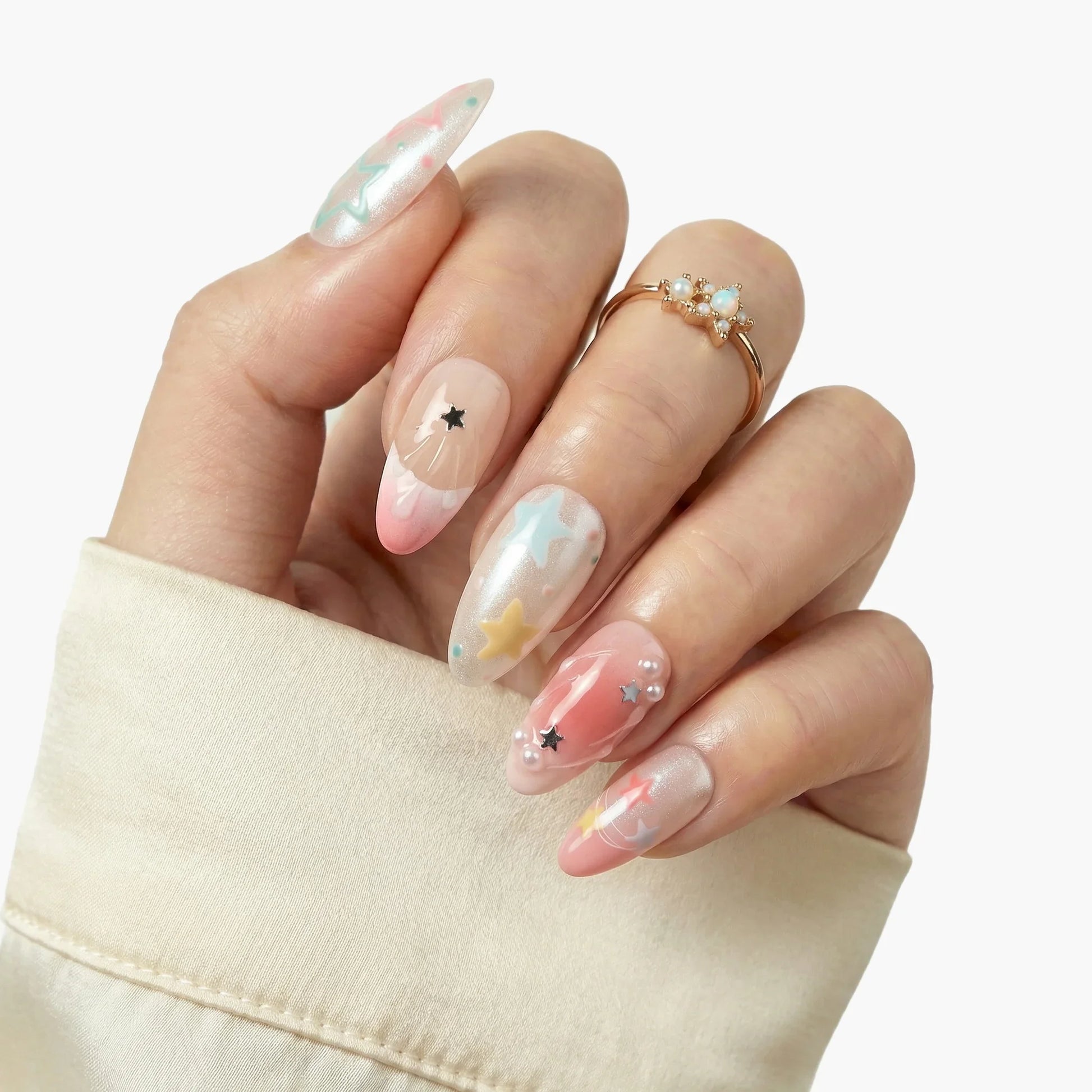 Hand with long press-on nails featuring pastel star designs and pearl accents