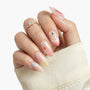 Hand with long press-on nails featuring pastel star nail art and 3D pearl accents