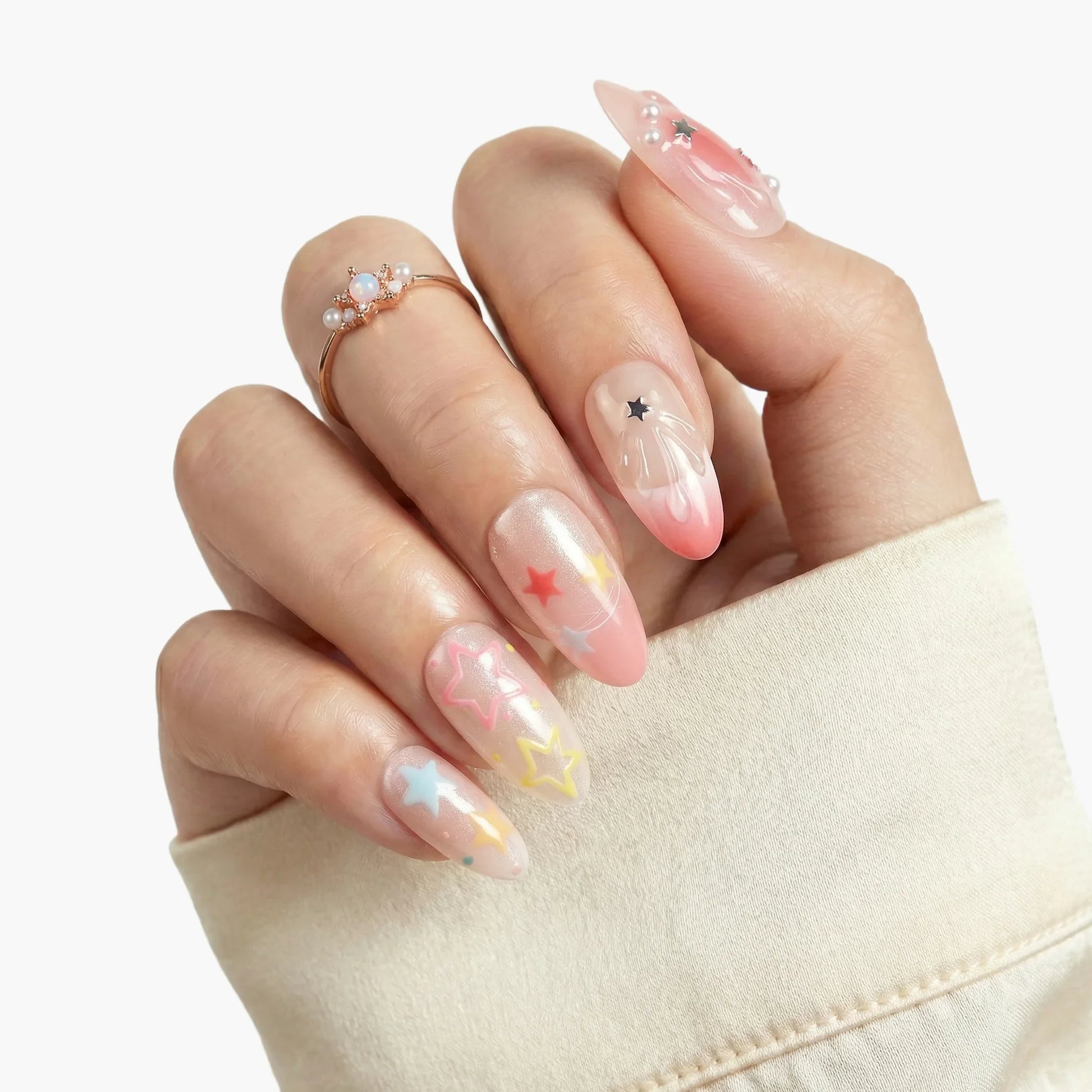 Hand with long press-on nails featuring pastel star nail art and 3D pearl accents