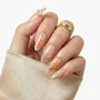 Hand with elegant press-on nails featuring gold koi fish art, pearls, and glitter tips