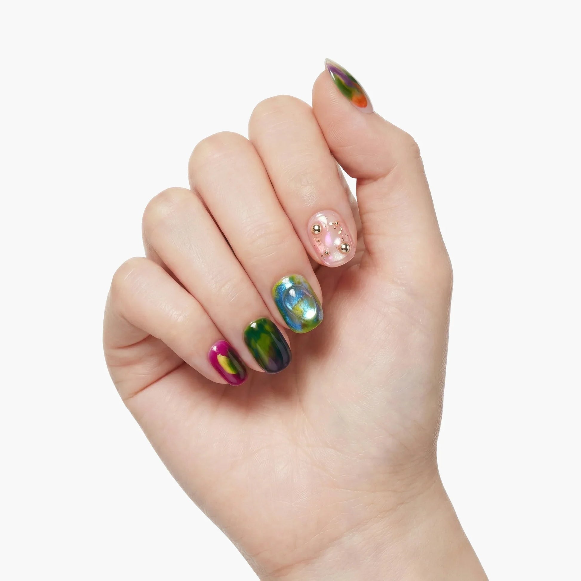 Hand with multicolored marble press-on nails and pink accent nail with gold studs