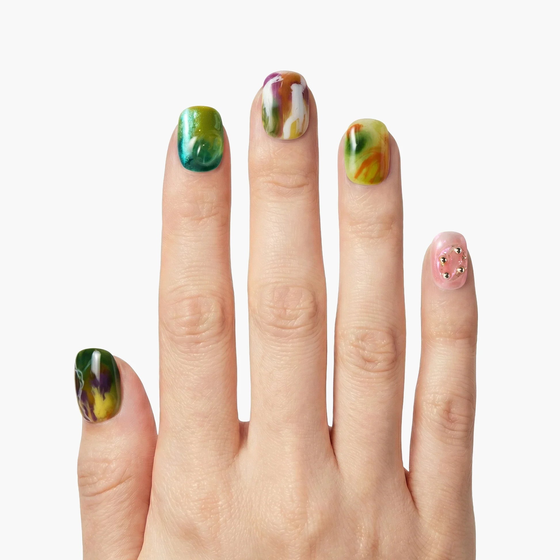 Hand with colorful marble press-on nails and pink accent nail with gold studs