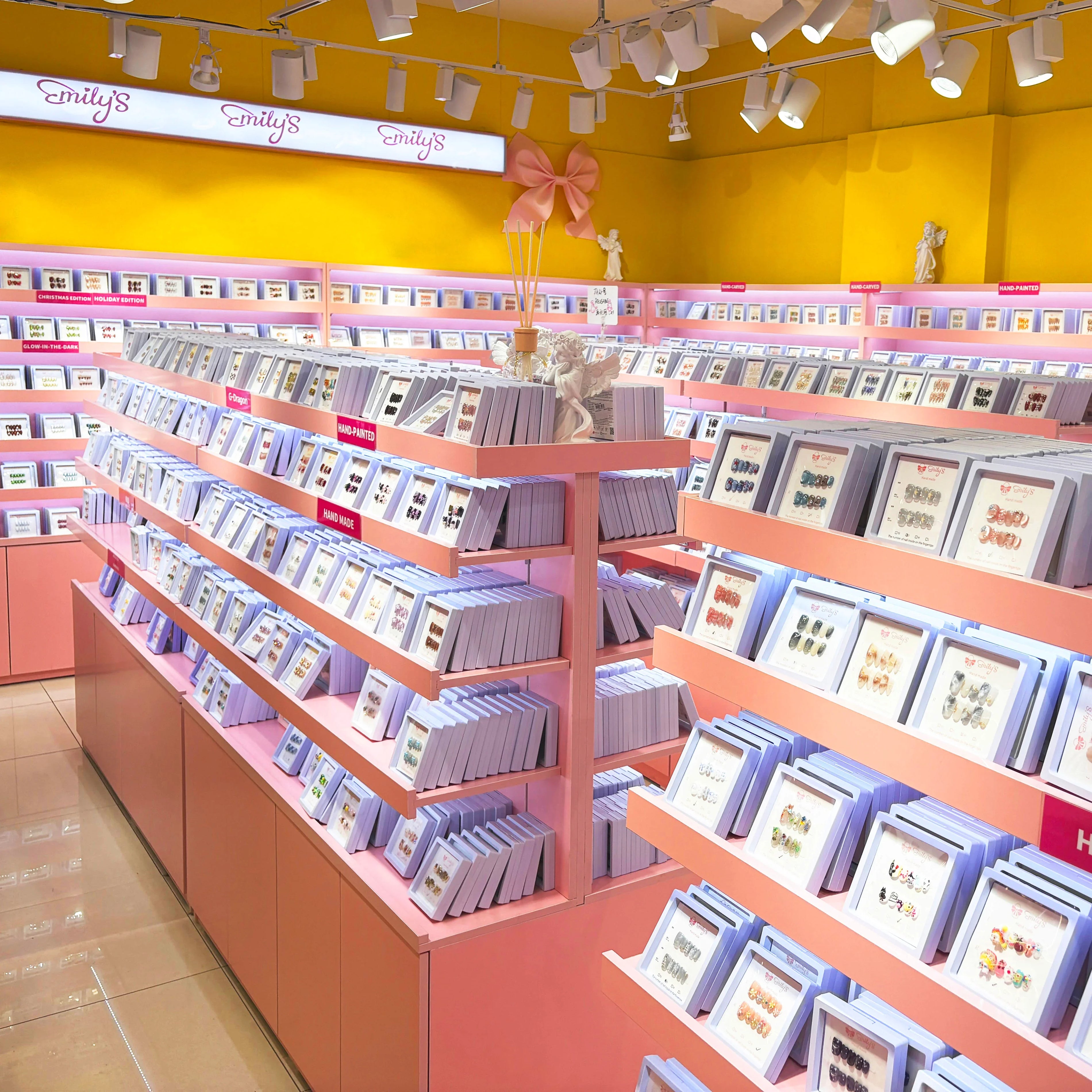 Bright display of handmade press-on nail sets arranged on pink shelves in a nail store