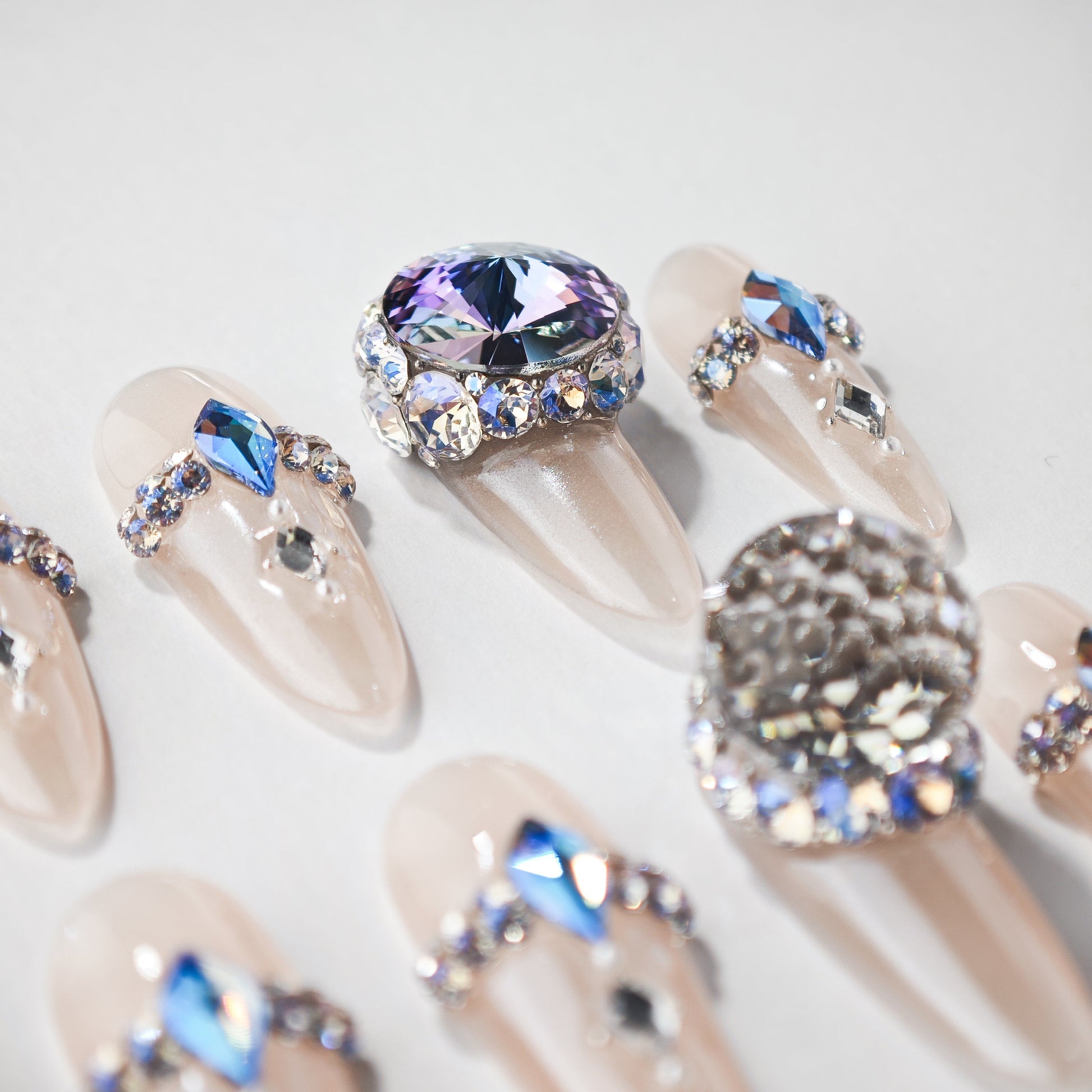 Handmade press-on nails with nude base and blue crystal rhinestone accents