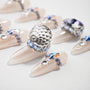 Glossy nude press-on nails with large crystal and blue rhinestone accents, luxury nail art