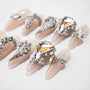 Nude press-on nails with large crystal and rhinestone 3D embellishments on white background