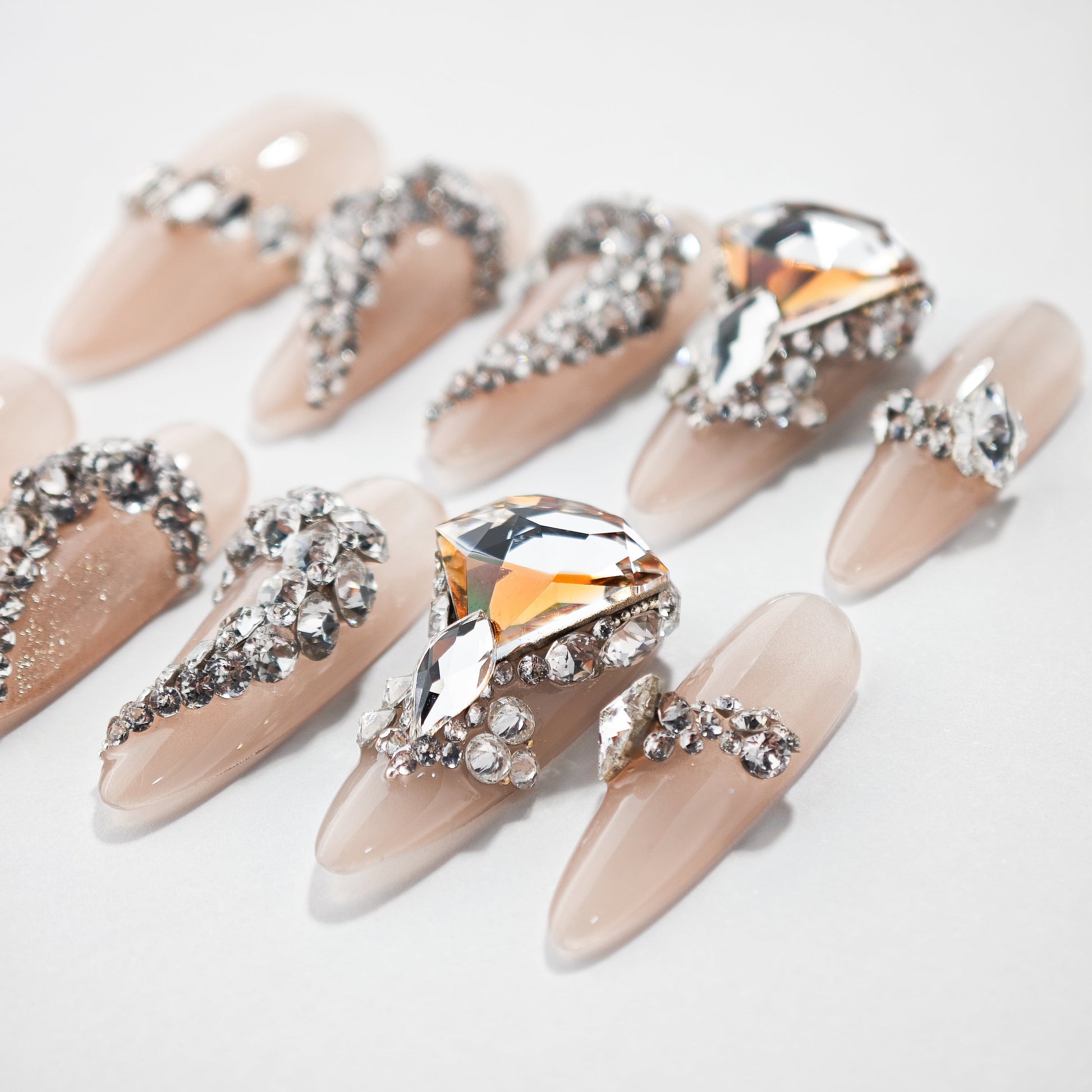 Nude press-on nails with large crystal and rhinestone 3D embellishments on white background