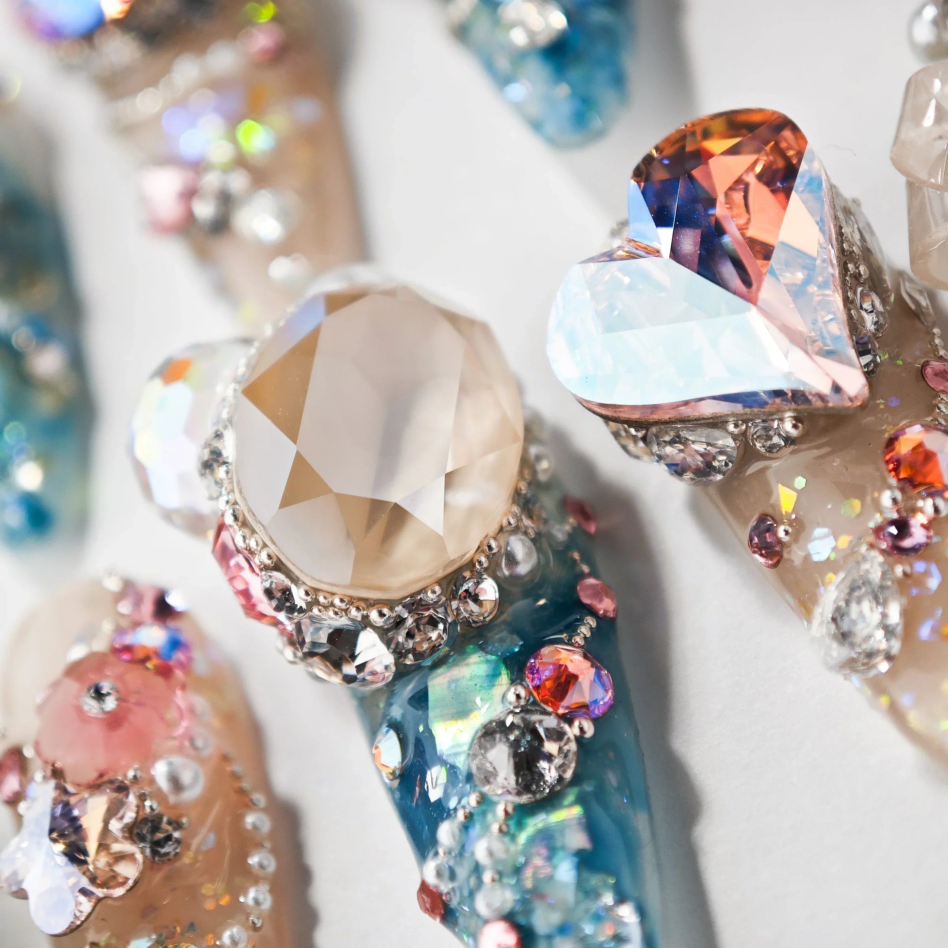 Handmade press-on nails with large gem accents, iridescent crystals, and blue glitter details.