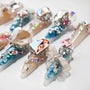 Handmade press-on nails with blue, beige, and pink base, decorated with large gemstones and crystals