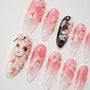Handmade press-on nails with pink gradient, 3D floral accents, and anime girl face design