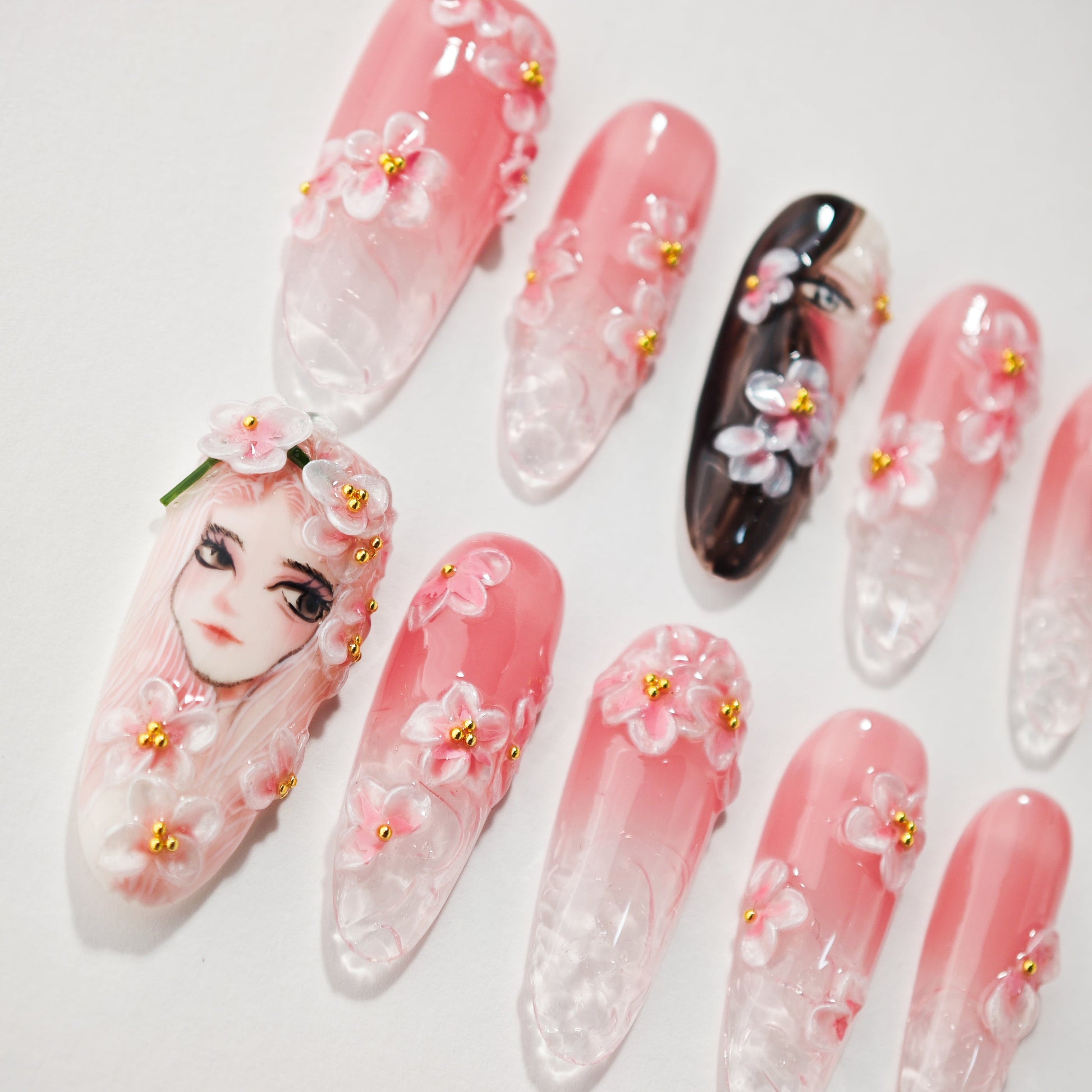 Handmade press-on nails with pink gradient, 3D floral accents, and anime girl face design