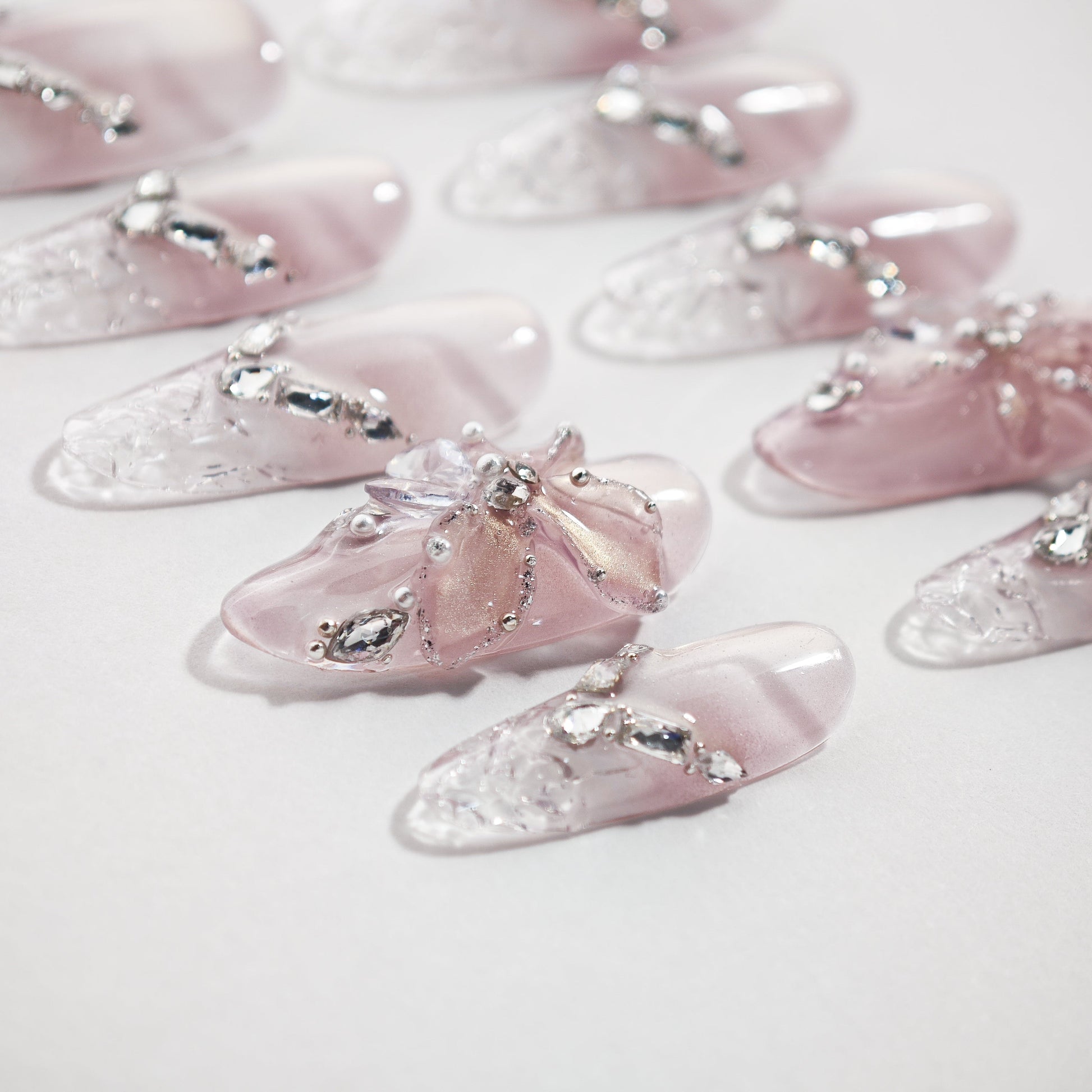 Handmade pink ombre press-on nails with 3D floral accents and crystal rhinestone details
