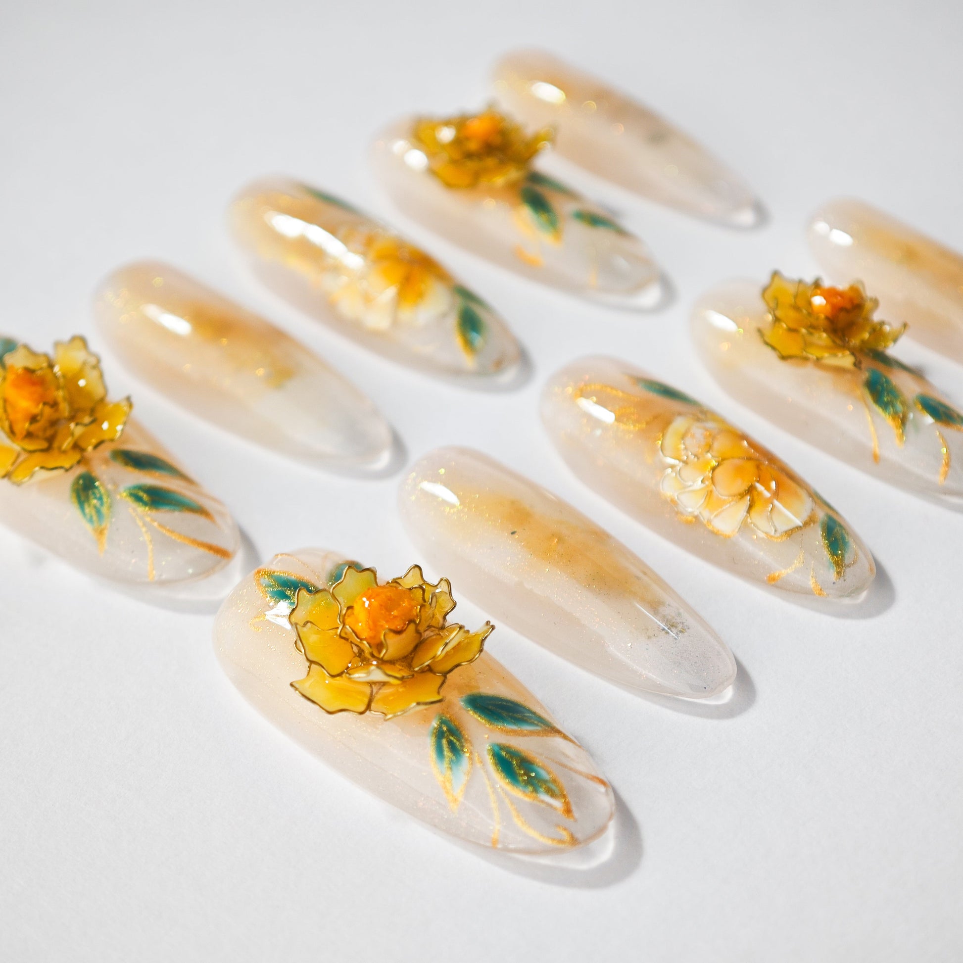 Handmade press-on nails with yellow 3D floral designs and green leaves on a glossy base