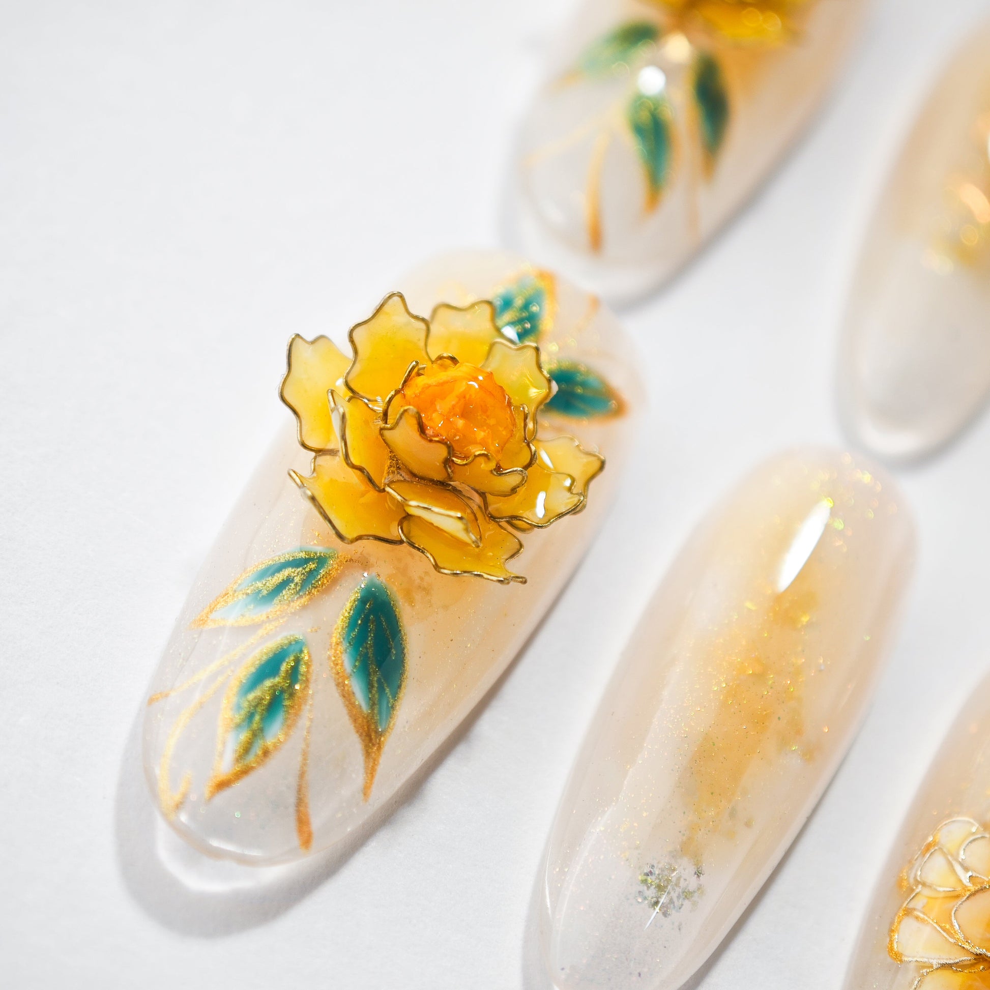 Handmade press-on nail with 3D yellow flower and green leaves on glossy nude base