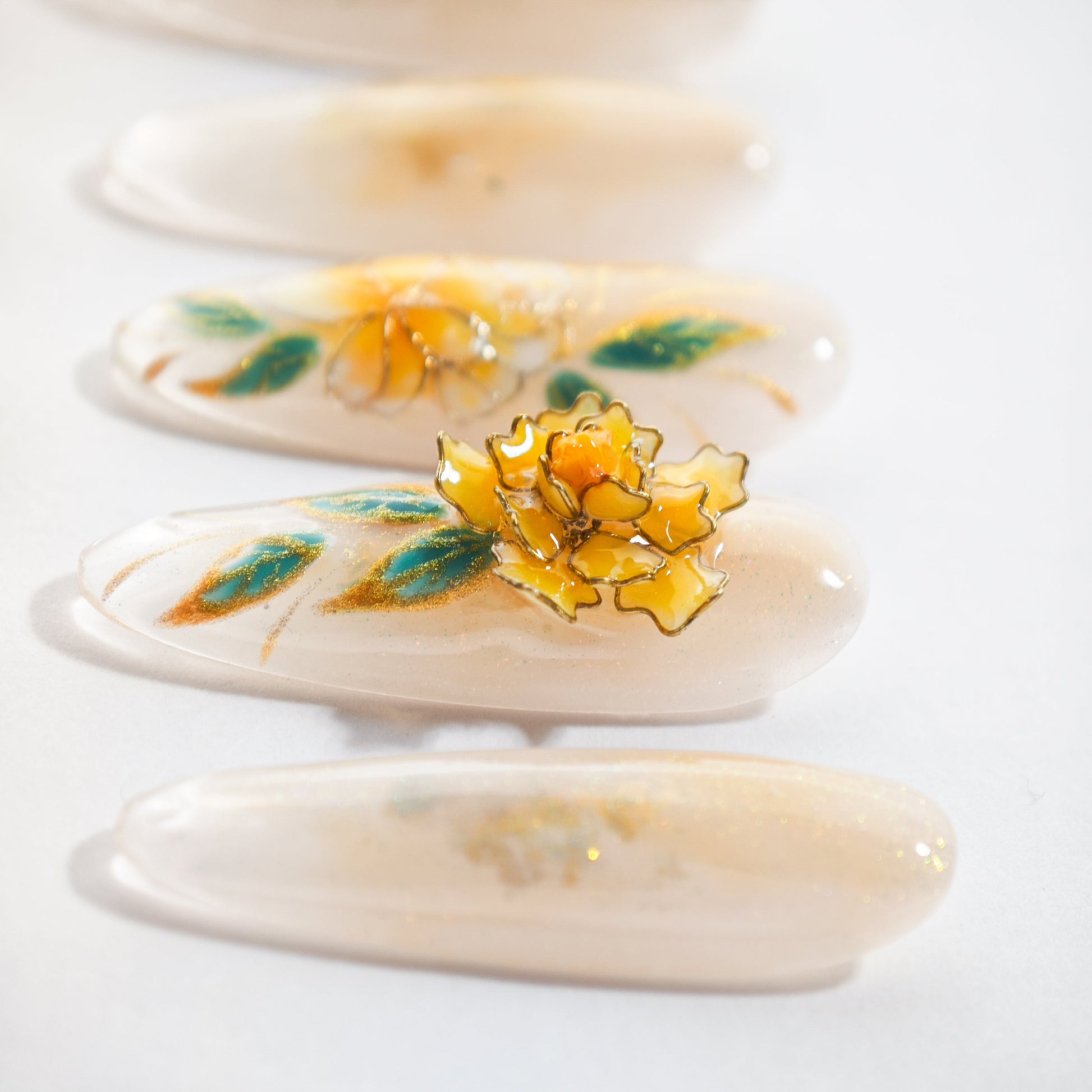 Handmade press-on nails with 3D yellow flower and green leaf design on a soft nude base