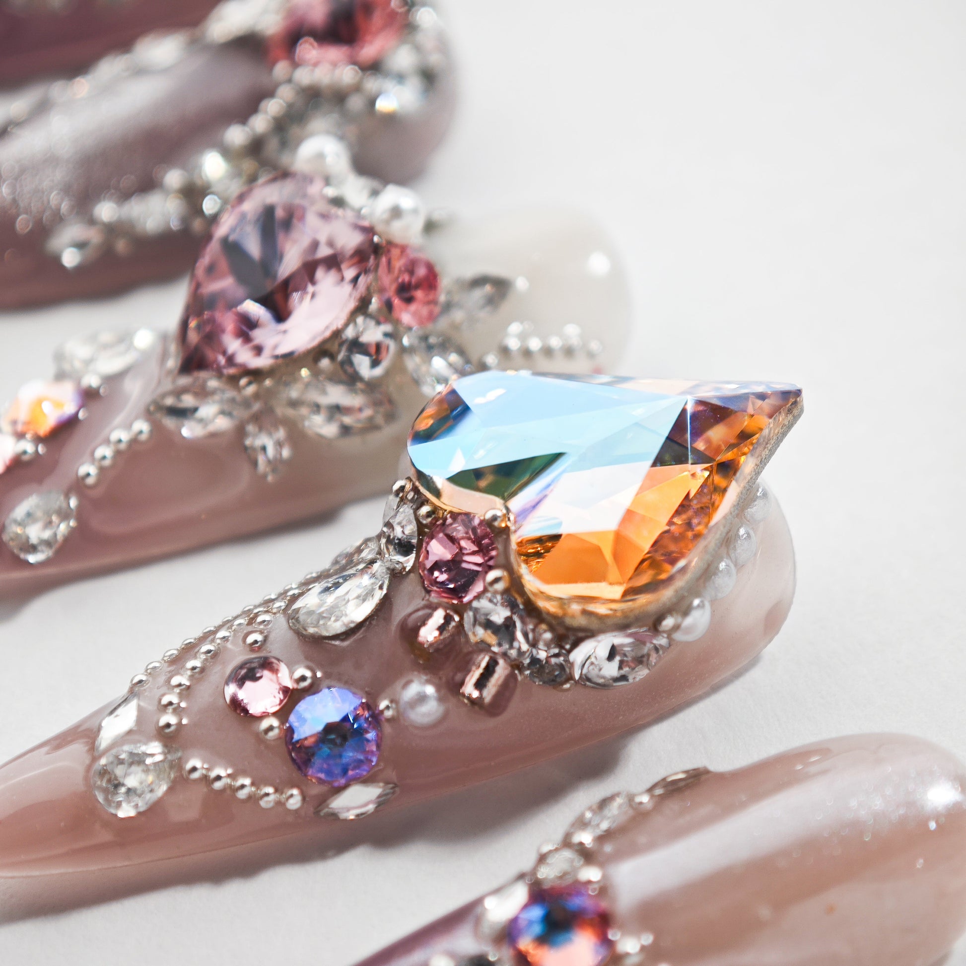 Handmade press-on nails with multicolored crystals, heart gems, and intricate 3D nail art