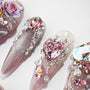 Handmade press-on nails with pink hearts, rhinestones, gems, and 3D floral art