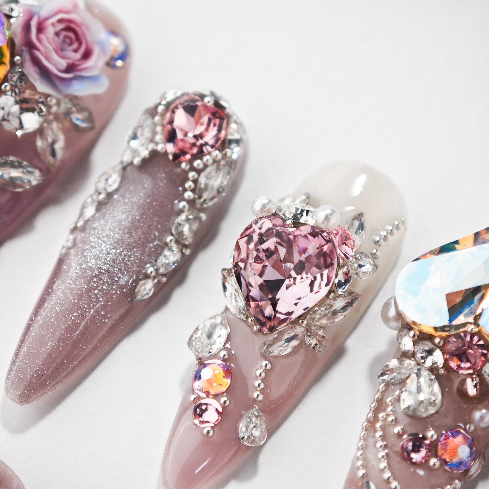 Handmade press-on nails with pink hearts, rhinestones, gems, and 3D floral art