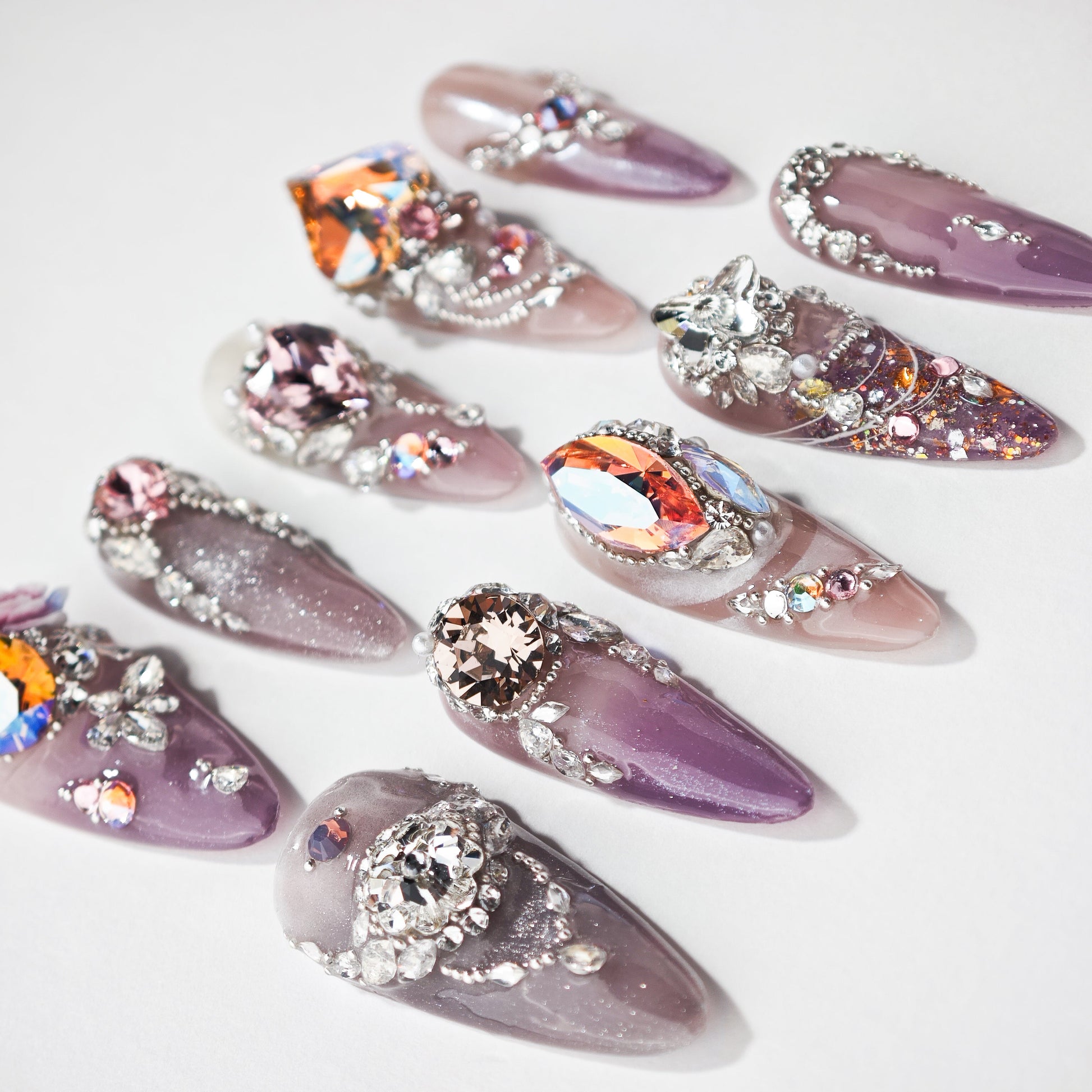 Purple ombre press-on nails with large rhinestones, silver gems, and glitter accents