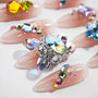 Handmade press-on nails with nude base, embellished with colorful rhinestones and glitter.