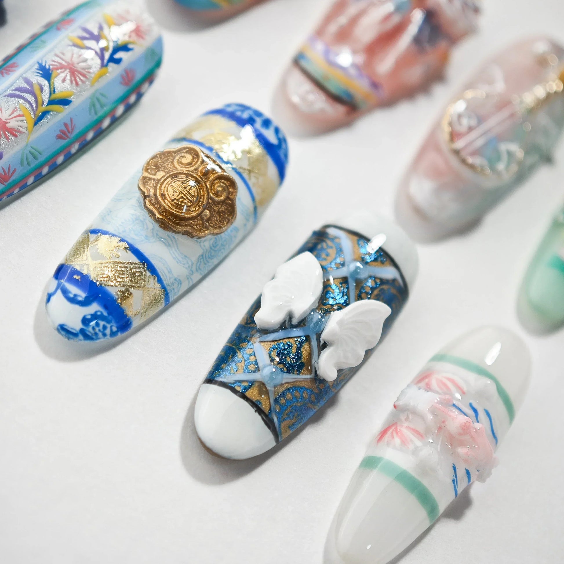 Handmade press-on nails with intricate 3D butterfly, gold, and floral designs on white background