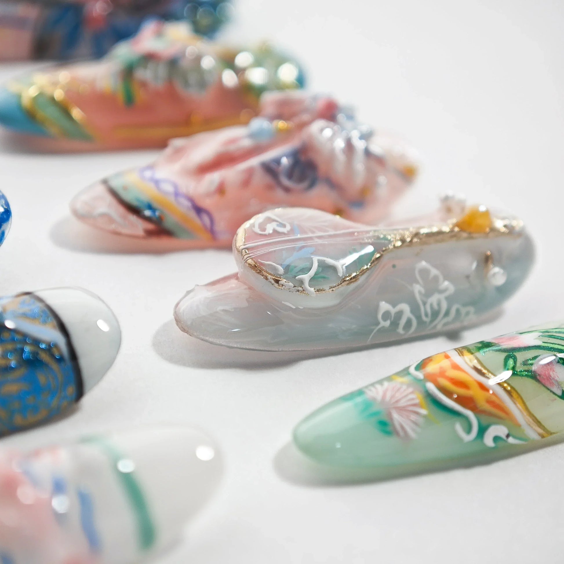 Handmade press-on nails with intricate floral and 3D designs on a white background.