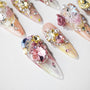 Handmade press-on nails with 3D gem designs, sparkling crystals, floral accents, and pastel colors