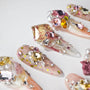 Handmade press-on nails with 3D gems, pearls, and glitter on a pink and nude gradient base