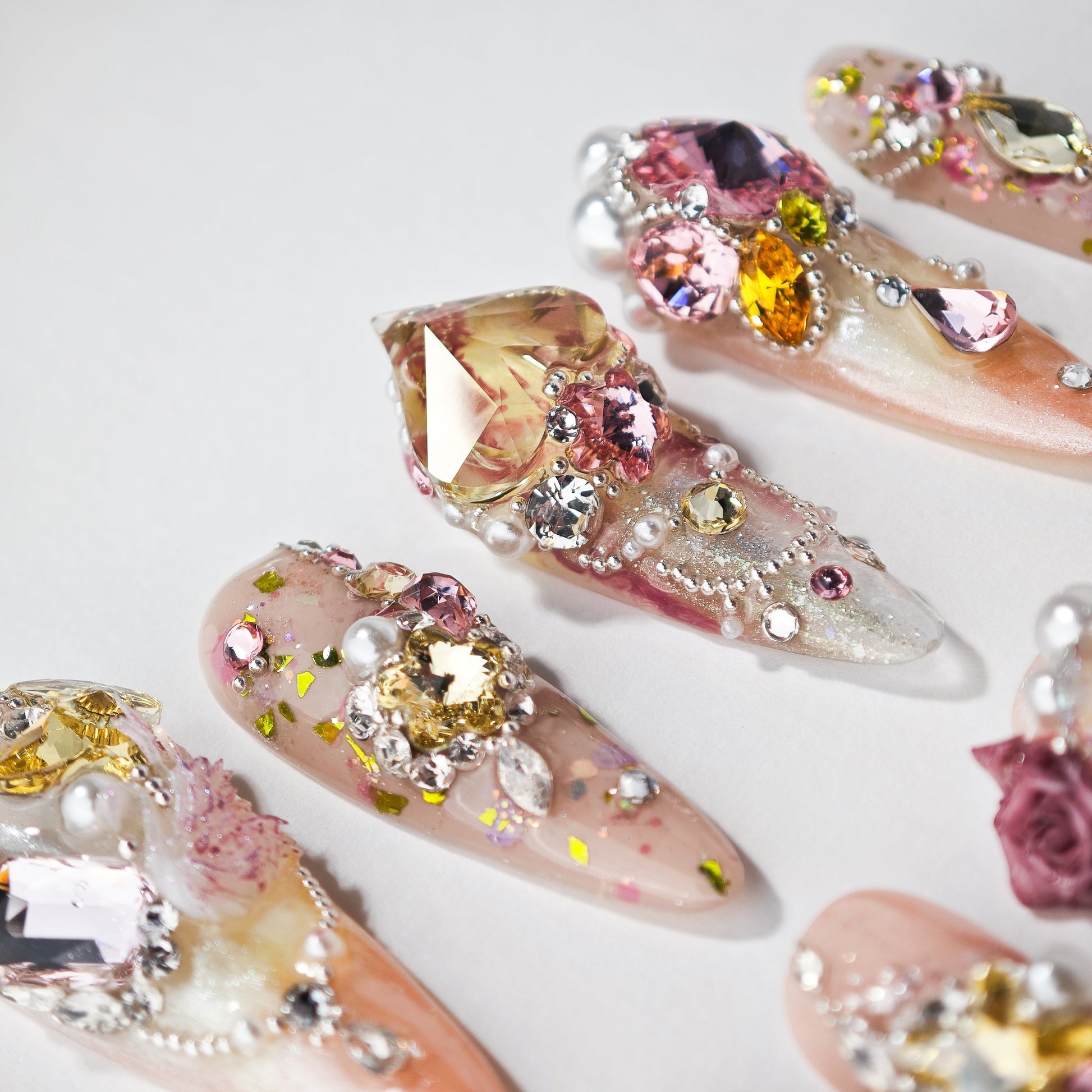 Handmade press-on nails with 3D gems, pearls, and glitter on a pink and nude gradient base