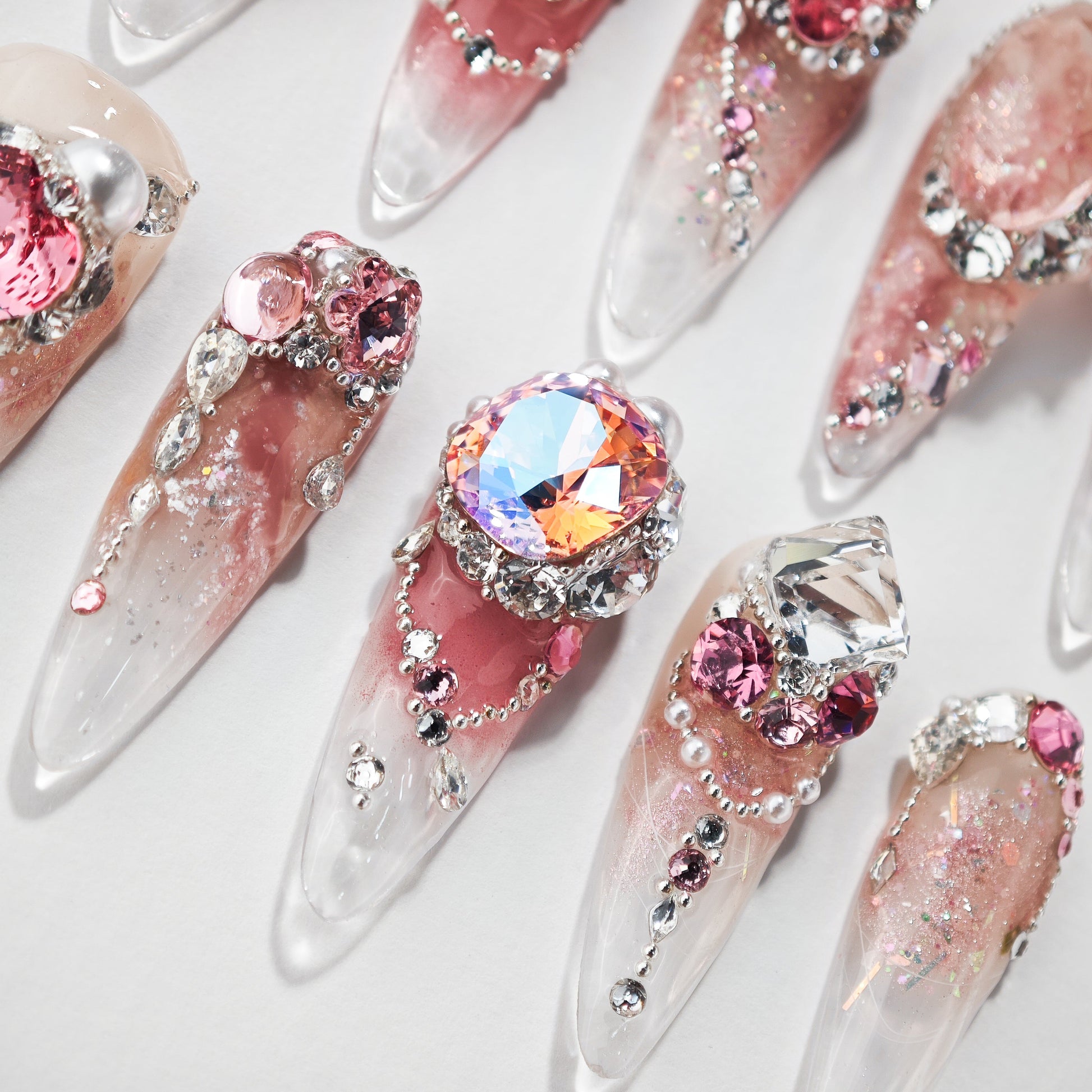 Handmade press-on nails with pink ombre, large rhinestones, and glitter embellishments